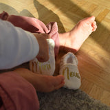 bebe tient dans sa main des chaussons de naissance ou annonce de grossesse personnalises mini nous de chez vic et pic