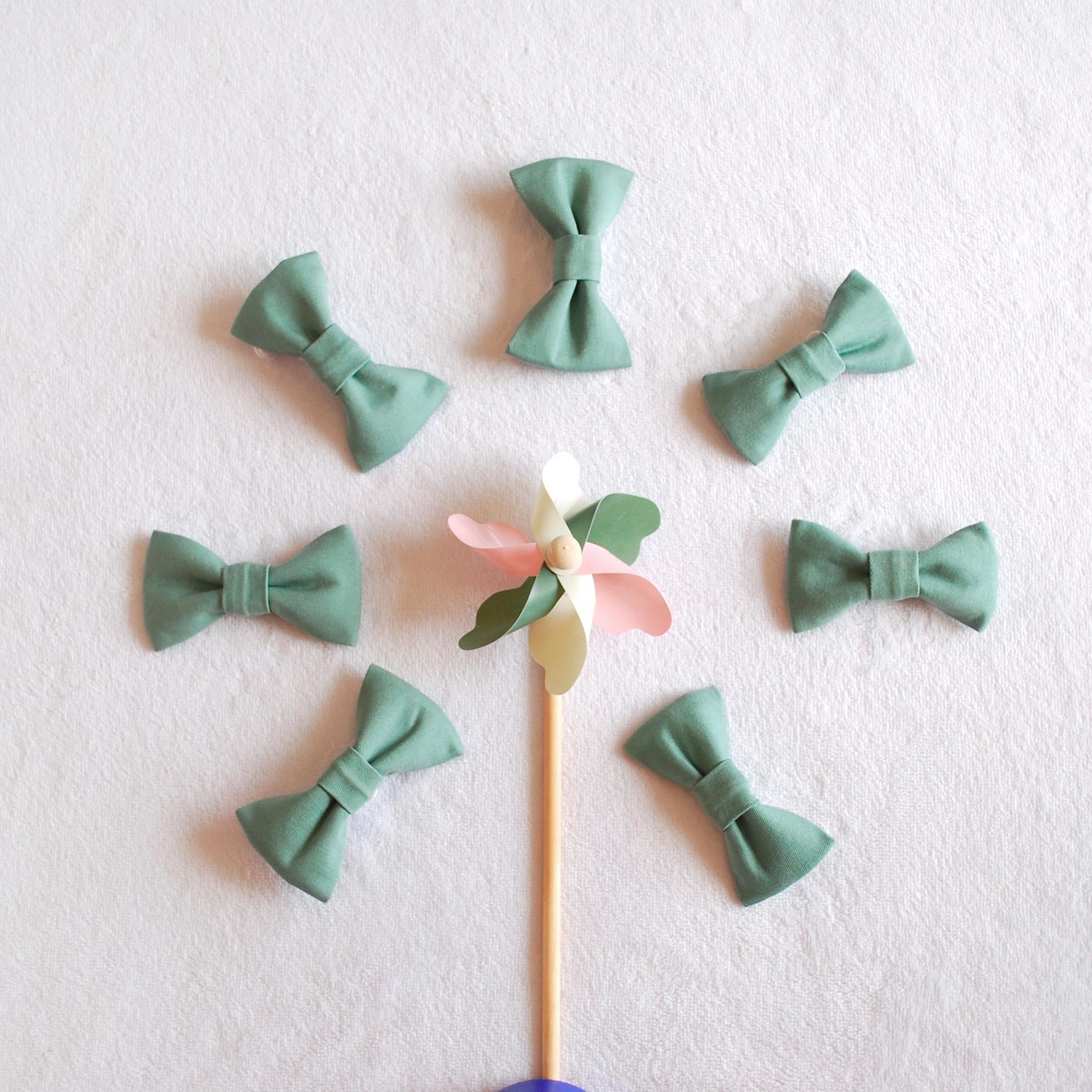 nœuds-papillon-en-tissu-vert-disposés -autour-d’un-moulin-a-vent-en-bois