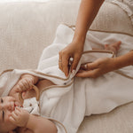 Cape de bain bébé blanche en gaze de coton, maman enveloppant son bébé après le bain