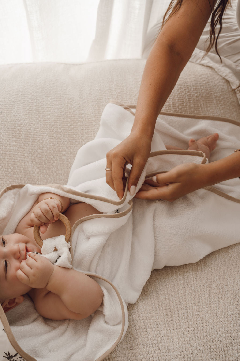 Cape de bain bébé blanche en gaze de coton, maman enveloppant son bébé après le bain