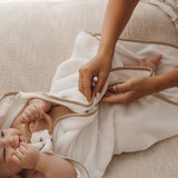 Cape de bain bébé blanche en gaze de coton, maman enveloppant son bébé après le bain
