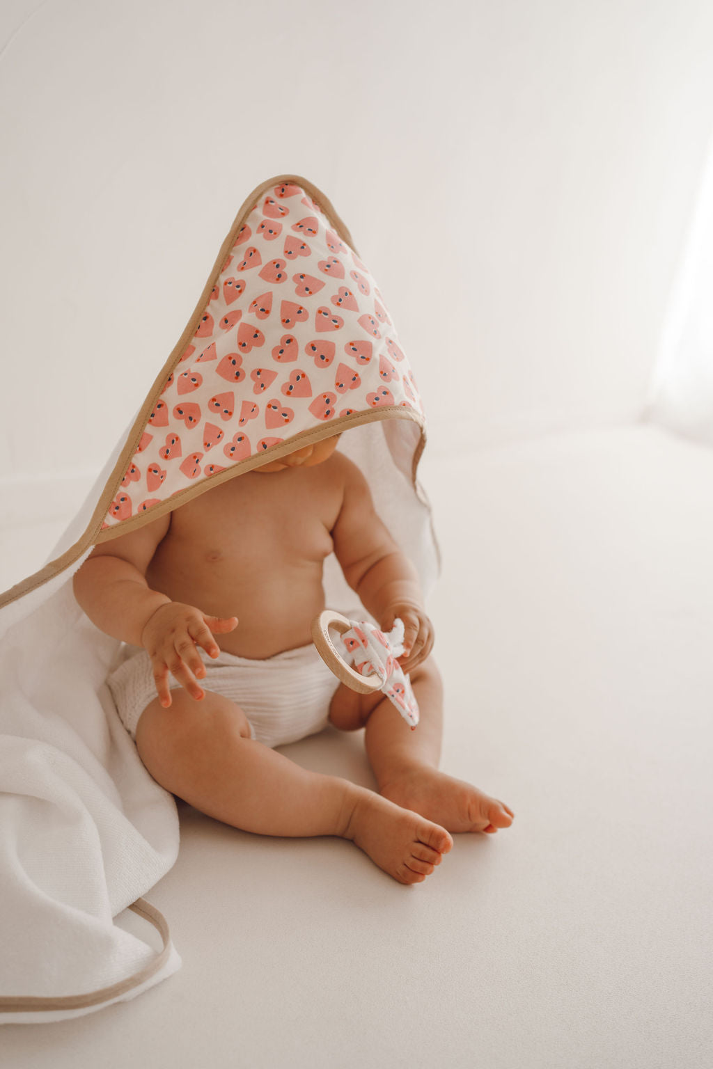 photo cape de bain love et hochet love porté par un bébé