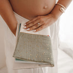 Protège-carnet de santé bébé en gaze de coton kaki avec détails dorés, porté par une maman